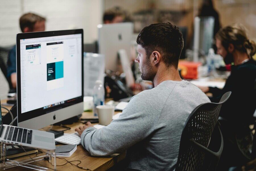 Developers at desks with monitors in a bright office